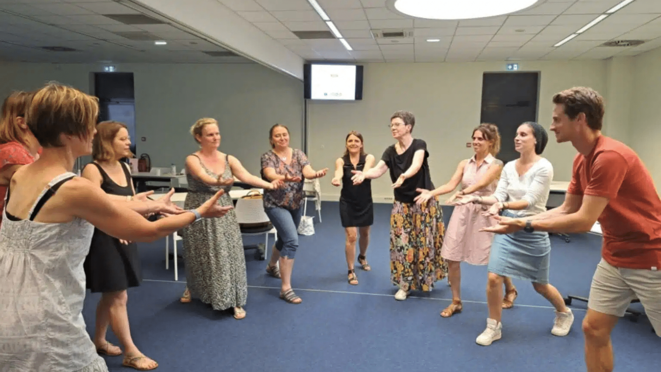 Participants engagés dans une activité interactive en cercle lors d'une formation en salle, favorisant la collaboration et l'apprentissage