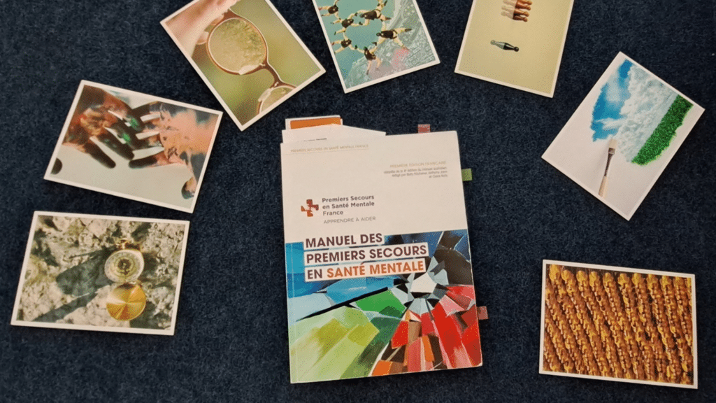 Manuel des Premiers Secours en Santé Mentale entouré de cartes illustrées utilisées lors d'une formation